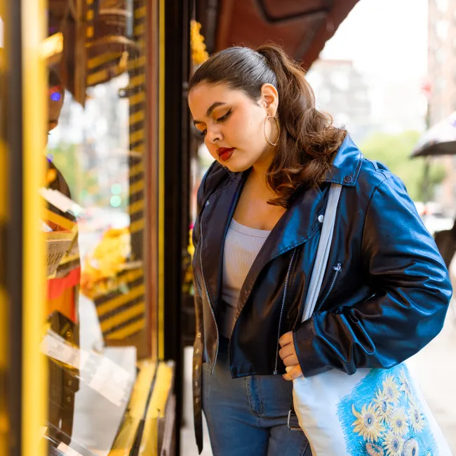 photo of a young woman shopping and looking at the storefront display on a rainy day