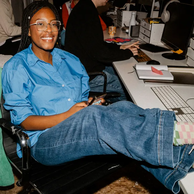 photo of smiling female sitting with feet up on table at office