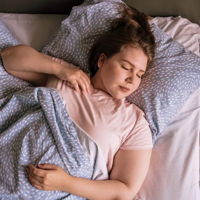 photo of a young woman sleeping on bed at home