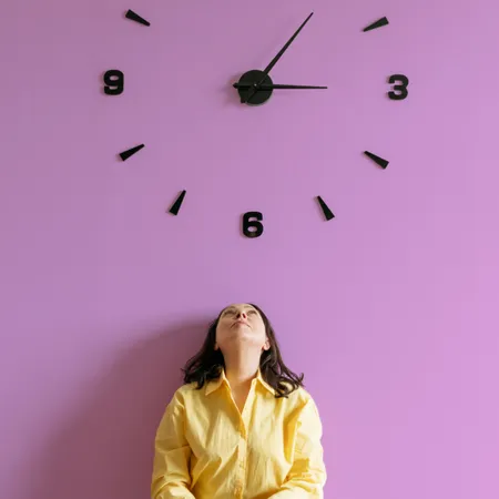photo of a woman sitting under a a large wall clock