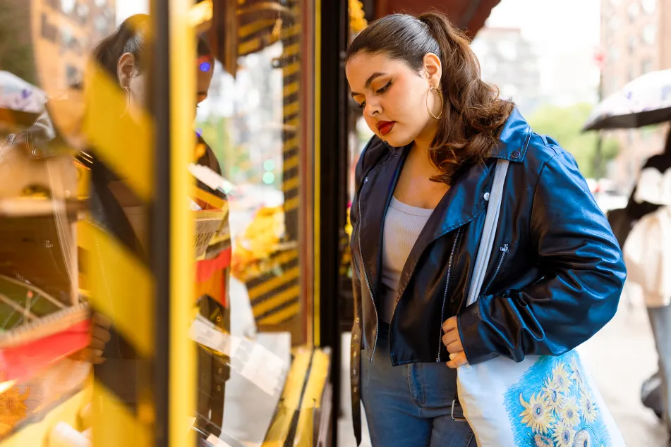 photo of a young woman shopping and looking at the storefront display on a rainy day