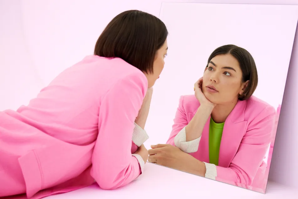 photo of woman looking at her reflection in mirror