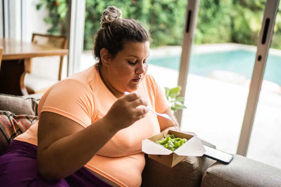photo of a woman eating a salad at home