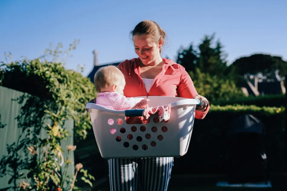 photo of a happy mother lifting laundry basket with baby girl in it