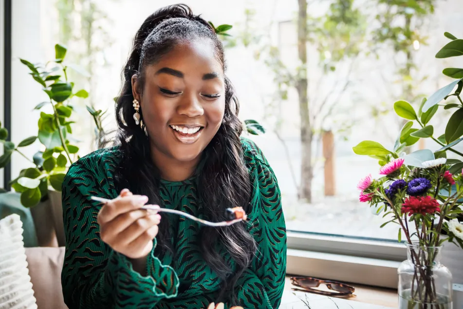 photo of a smiling young black woman enjoying her meal
