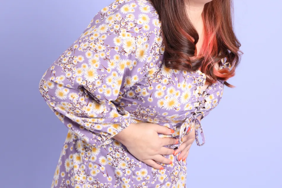 photo of an Asian woman holding her stomach in pain