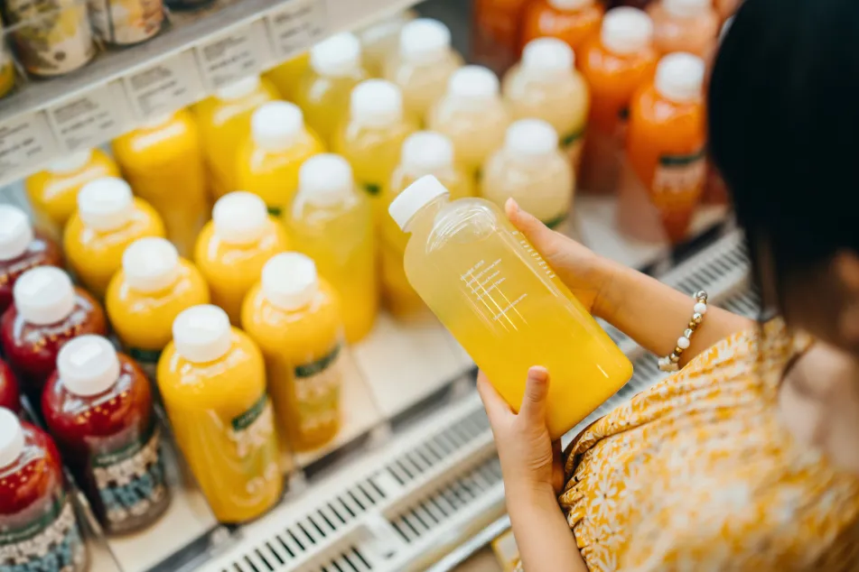 photo of an Asian woman looking at fresh juices in a supermarket