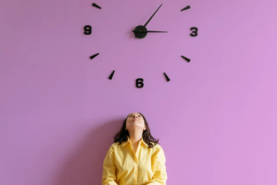 photo of a woman sitting under a a large wall clock
