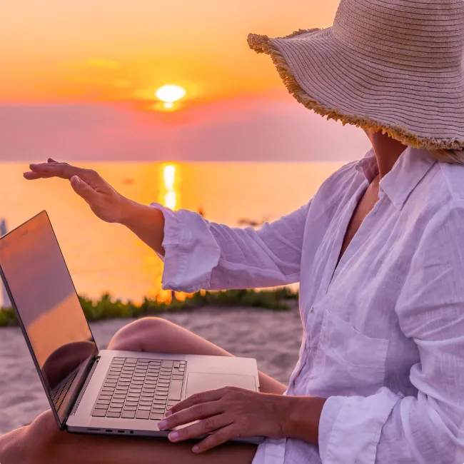 photo of a woman closing laptop while relaxing on chair and looking at beautiful sunset