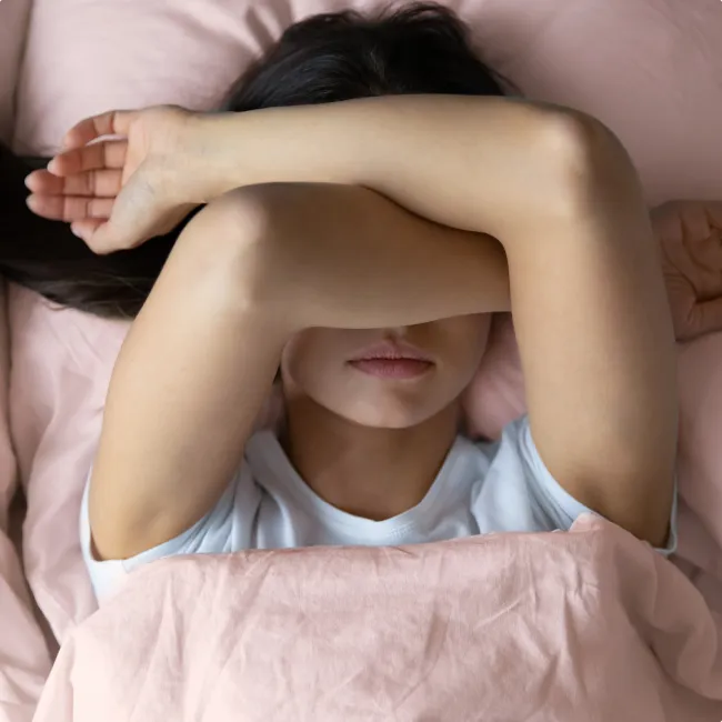 photo of a  young female lying in bed unwilling to wake up 