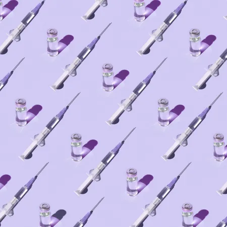 photo of a pattern of vials and syringes with a vaccine on a purple background