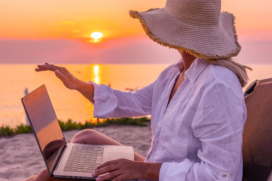 photo of  a woman closing laptop while relaxing on chair and looking at beautiful sunset