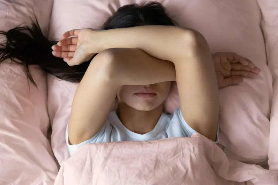 photo of a  young female lying in bed unwilling to wake up 