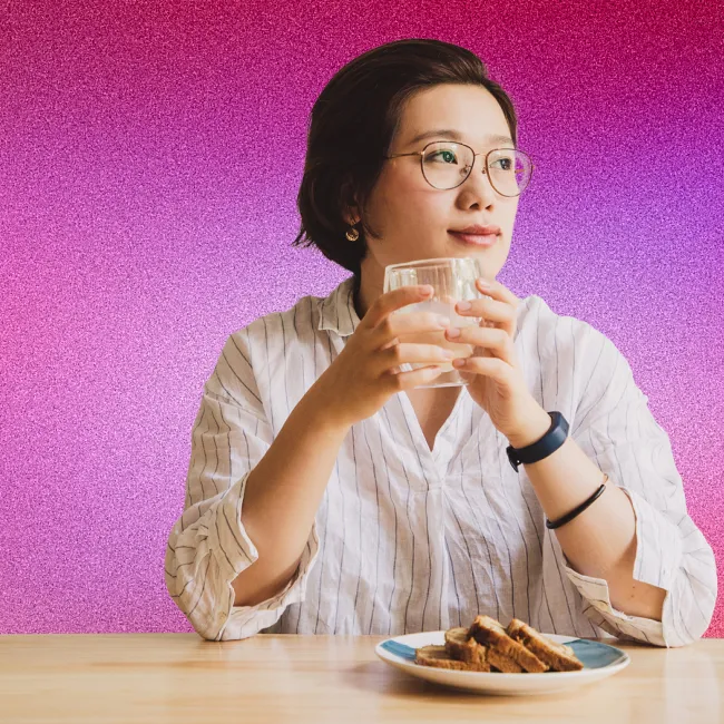 photo of woman holding glass of water looking out window