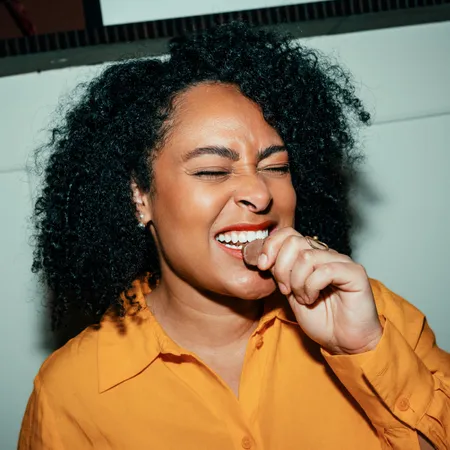 photo of Woman laughing and biting a chocolate
