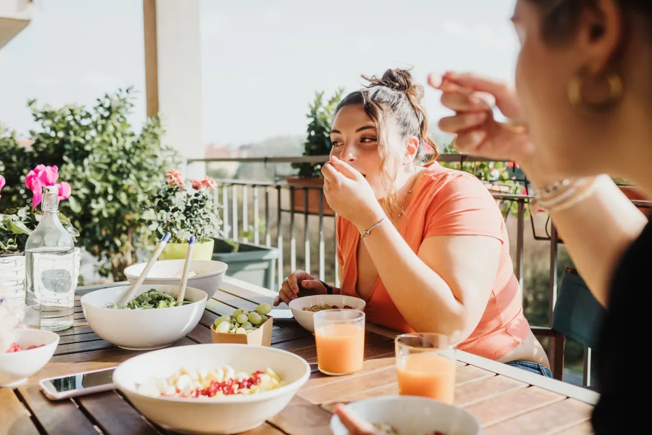 photo of  friends eating meal on balcony
