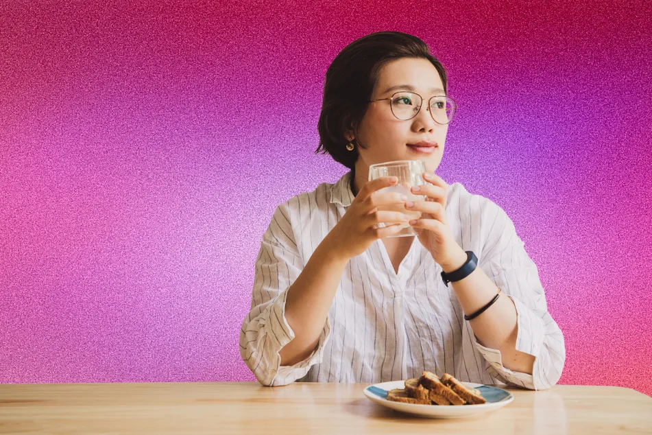 photo of woman holding glass of water looking out window