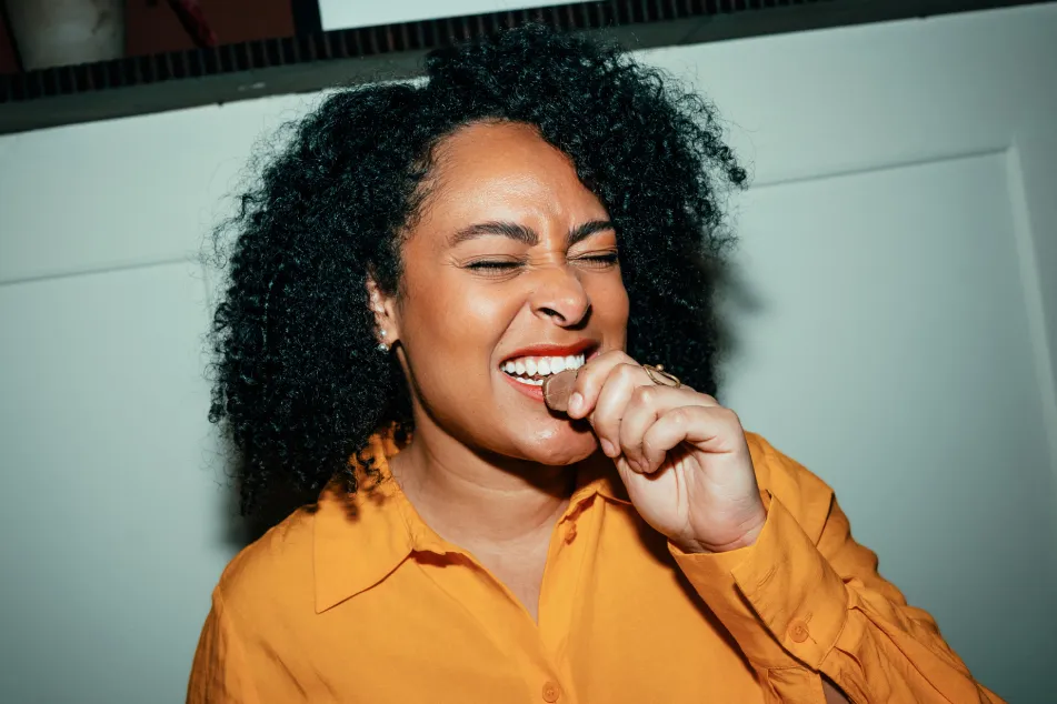 photo of Woman laughing and biting a chocolate