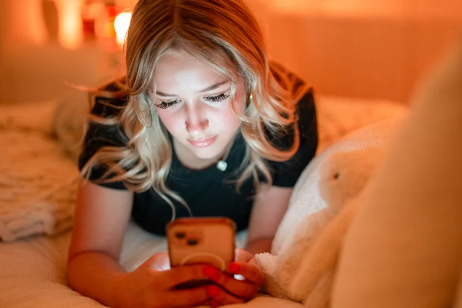 photo of a man lying in bed and using smartphone