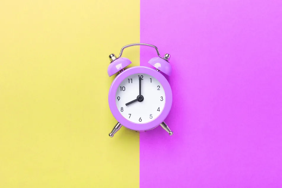 photo ofphoto of purple alarm clock on two tone color purple and yellow background
