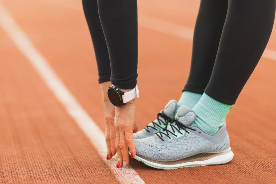 photo of woman stretching at an outdoor track