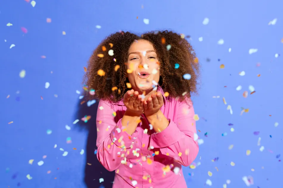 photo of happy woman blowing confetti