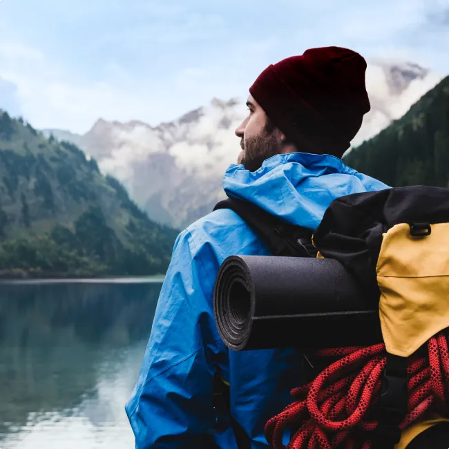 photo of hiker standing at mountain lake 