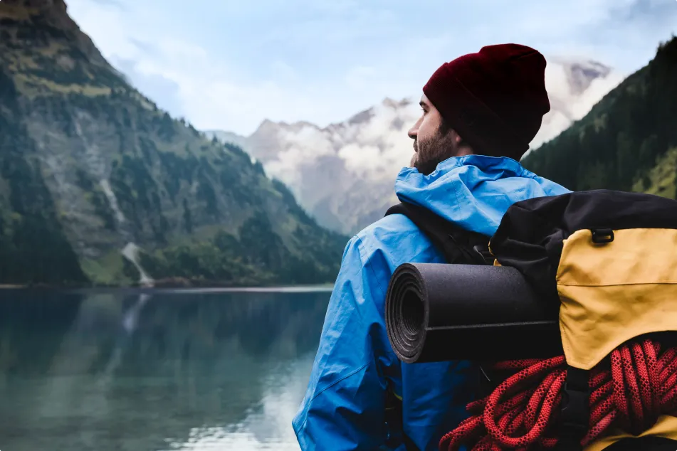 photo of hiker standing at mountain lake 