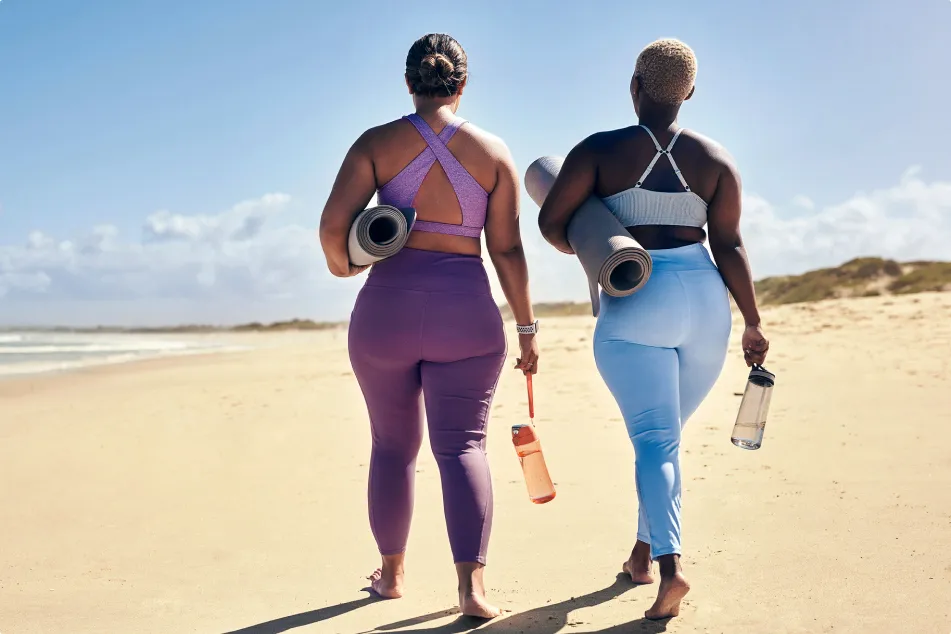 photo of women walking on beach with yoga mats