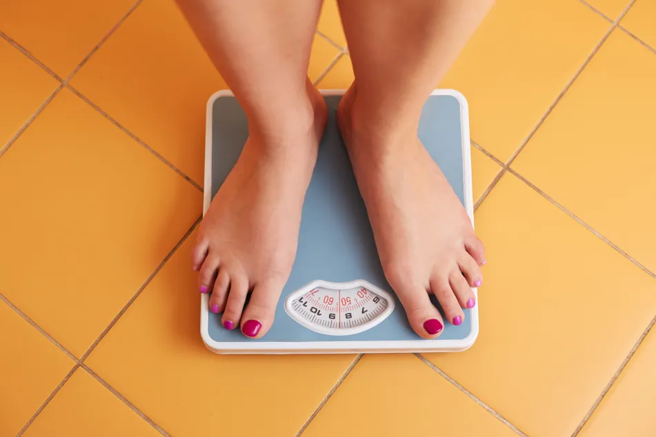 photo of female feet standing on a bathroom scale