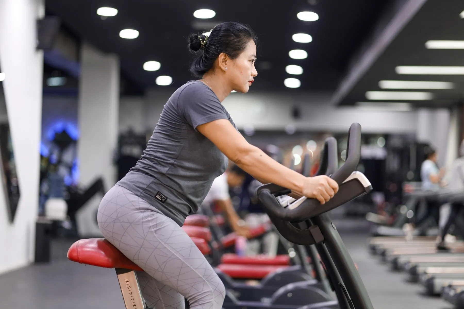 photo of woman riding stationary bike in gym